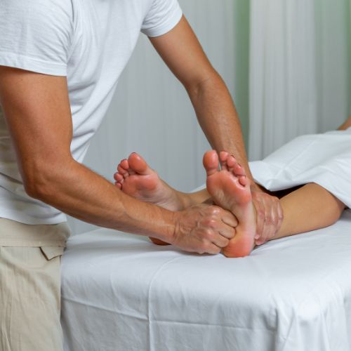 Profissional Massoterapeuta aplicando a Reflexologia Podal no cliente.